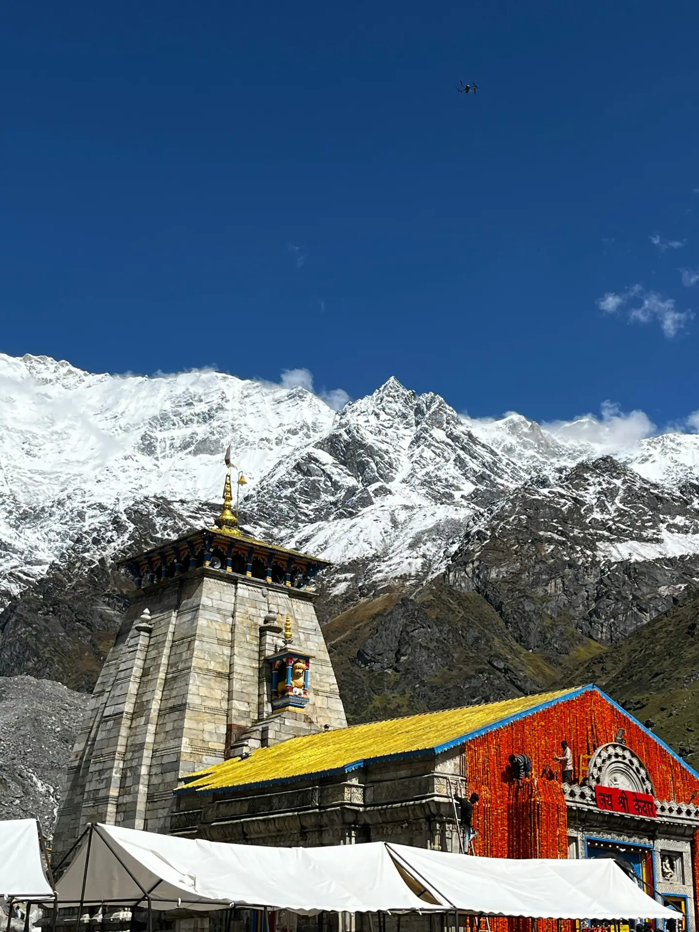 Majestic view of Kedarnath Temple against snow-capped Himalayan peaks under clear blue sky.